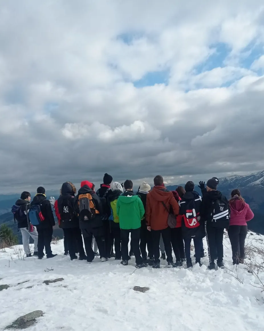 El grupo de espaldas en una cima nevada mirando las montañas